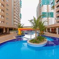 Piscina rodeada por palmeiras e um edifício com vários andares.
