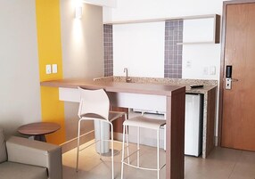 Uma cozinha compacta com ilha integrada, banquetas e uma pequena mesa redonda.
