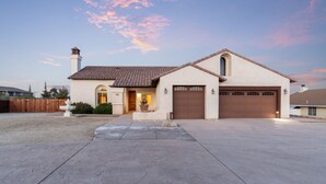 A single-story house with a brown garage, a front porch, and a small fountain. - Home in a boulder-filled neighborhood. 15 minutes to Joshua Tree National Park! (Yucca Valley)