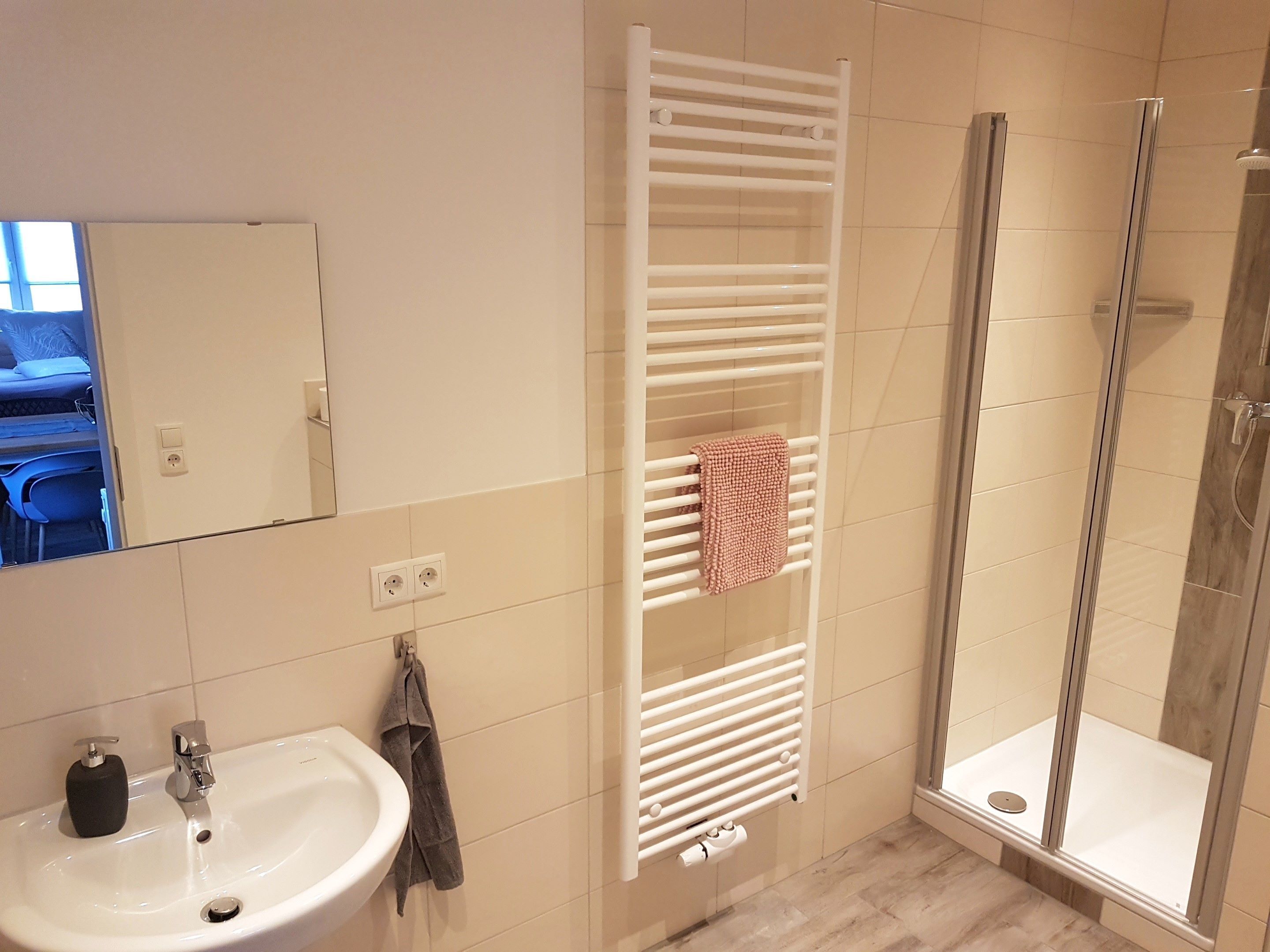 A bathroom with a white sink, a towel rack, and a glass shower enclosure.