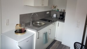 A compact kitchen with a stainless steel sink, a coffee maker, and a small refrigerator. - Ferienwohnung Busch (Rust)