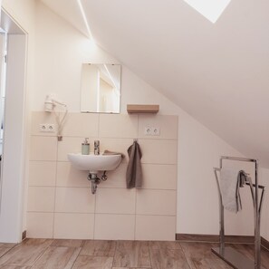 A modern bathroom with a white sink, a mirror, and a towel rack. - Ferienwohnung Busch (Rust)