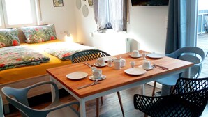 A room with a bed, a dining table set for two, and a TV mounted on the wall. - Ferienwohnung Busch (Rust)