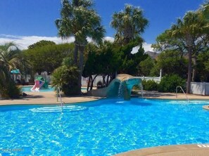 A swimming pool with a water slide and palm trees. - 180 Beach Club Villa (Fripp Island)