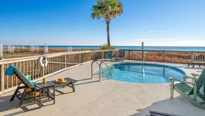 A pool area with lounge chairs, a lifebuoy, and a palm tree. - Beachfront, Pool, Amazing Views, and Sleeps 14 (Panama City Beach)