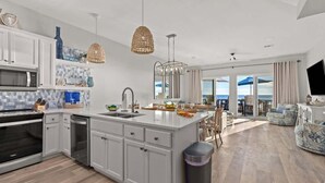 A modern kitchen with white cabinetry, a large island, and a view to the outdoors. - Beachfront, Pool, Amazing Views, and Sleeps 14 (Panama City Beach)