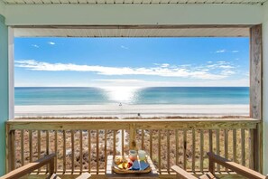 Une terrasse en bois offrant une vue sur une plage et l’océan.