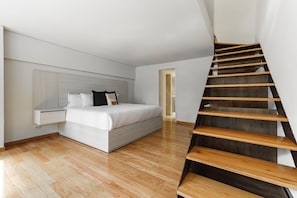 A modern bedroom with a wooden staircase, a bed, and a nightstand. - Horacio 1411 by Naya Homes (Mexico City)