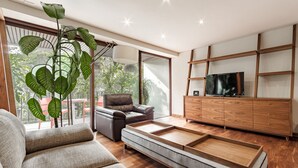 Ein modernes Wohnzimmer mit einer Couch, einem Couchtisch, einem Fernseher und einer Holzkommode.