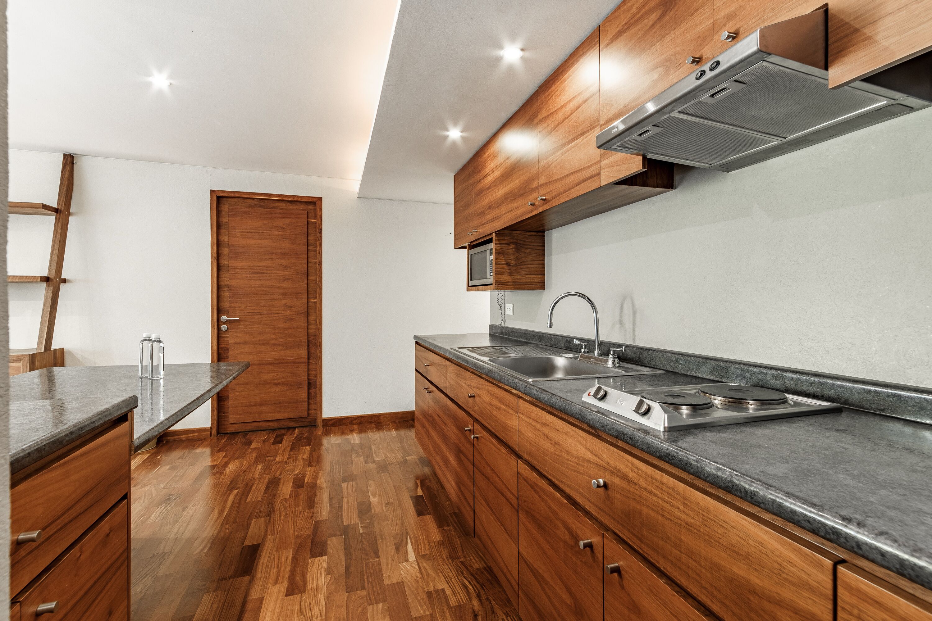 A modern kitchen with wooden cabinets, a stainless steel sink, and a built-in microwave.