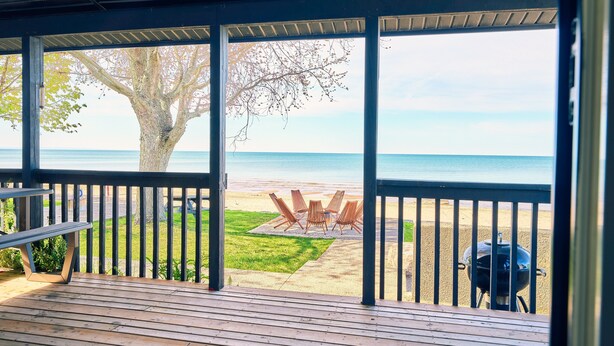 Um deque coberto com vista para uma praia e uma churrasqueira.