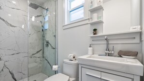Une salle de bain moderne avec une douche à parois de verre, des toilettes blanches et un lavabo doté d’un porte-serviettes.