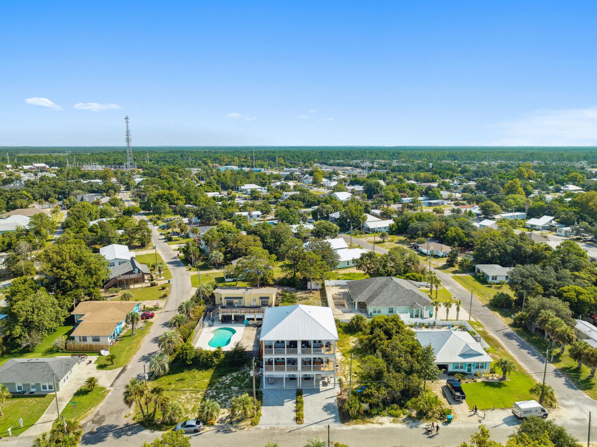 An aerial view of a residential area with houses, a swimming pool, and a large building with a balcony.
