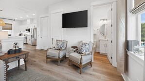 A modern kitchen with white cabinets, stainless steel appliances, and a flat-screen TV mounted above the counter. - Grand Retreat I! 4BR 5BA Sleeps 15! Private Pool! Luxury and Comfort Await! (Panama City Beach)