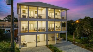 A two-story house with a balcony on the upper floor, a covered porch on the ground floor, and a garage. - Grand Retreat I! 4BR 5BA Sleeps 15! Private Pool! Luxury and Comfort Await! (Panama City Beach)