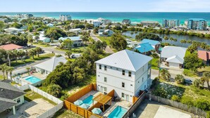 A residential area with a large house featuring a swimming pool, surrounded by other houses and a lake. - Grand Retreat I! 4BR 5BA Sleeps 15! Private Pool! Luxury and Comfort Await! (Panama City Beach)