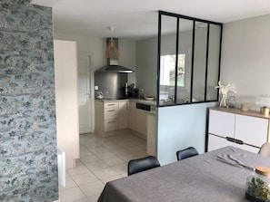 A modern kitchen with a built-in stove, a dining area with a table and chairs, and a view of the outdoors.