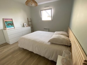 A bedroom with a bed, a dresser, a window, and a picture frame on the dresser.
