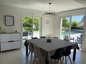 A dining area with a table, chairs, a pendant light, and a view of a swimming pool.