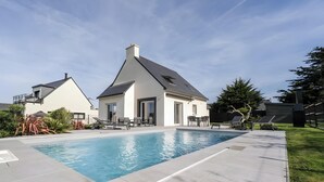 En bostadsfastighet med en swimmingpool, en uteplats med utemöbler och ett stort träd.