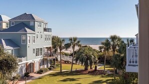 A beachfront property with a large house, a covered patio, and a view of the ocean. - Award-Winning Resort Amenities | Grand Pavilion 24 (Isle of Palms)