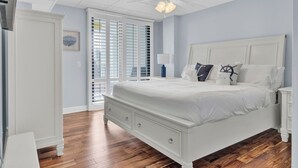 A bedroom with a white bed, a nightstand, a dresser, and a ceiling fan.