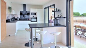 A modern kitchen with a central island, bar stools, and a dining area with a view. - Villa Pietra Avec Piscine Privée à 300 Mètres de la Plage (Conca)