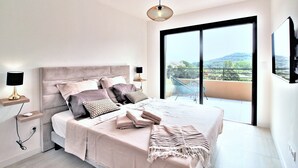 A modern bedroom with a large bed, bedside lamps, and a view of a balcony. - Villa Pietra Avec Piscine Privée à 300 Mètres de la Plage (Conca)