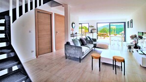 A modern living room with a grey sofa, a white coffee table, and a staircase with black railings. - Villa Pietra Avec Piscine Privée à 300 Mètres de la Plage (Conca)