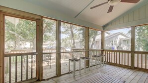 A covered porch with wooden flooring, a ceiling fan, and large windows offering views of a residential area. - Award-Winning Resort Amenities | Lake Village 10 (Isle of Palms)