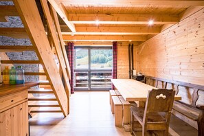 Un intérieur en bois comprenant une table à manger, des bancs et un escalier.