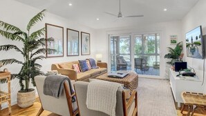 A spacious living room with a sofa, chairs, a coffee table, and a large potted plant. - Award-Winning Resort Amenities | Twin Oaks 22 (Isle Of Palms)