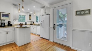 A kitchen with white cabinetry, a central island, and a view to a balcony. - Award-Winning Resort Amenities | Twin Oaks 22 (Isle Of Palms)