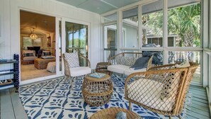 A covered porch with wicker furniture, a patterned rug, and a view of the outdoors. - Award-Winning Resort Amenities | Twin Oaks 22 (Isle Of Palms)