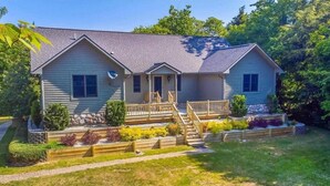 A two-story house with a front porch, a staircase leading to the entrance, and a landscaped front yard.
