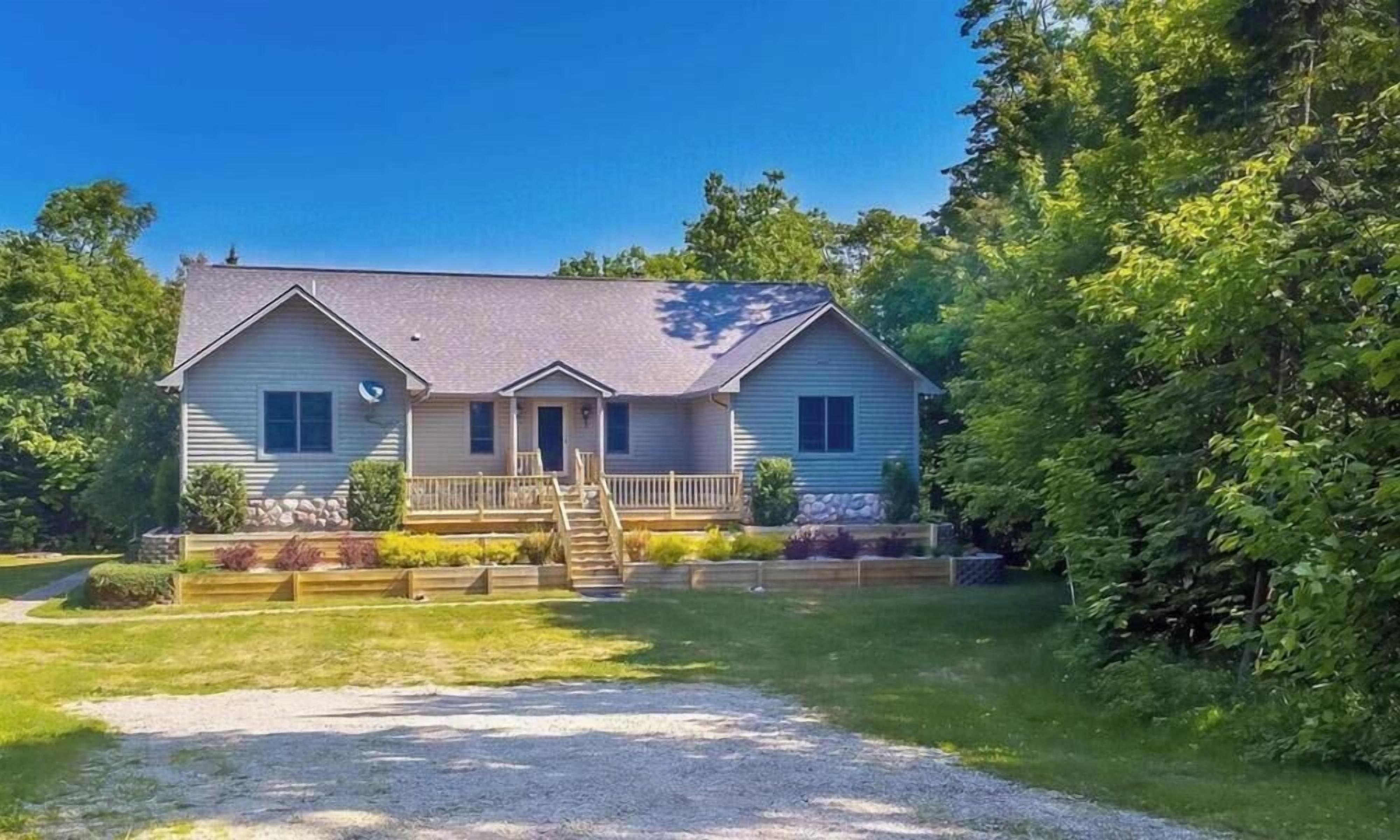 A two-story house with a front porch, a staircase leading to the entrance, and a driveway.