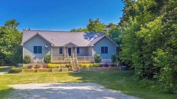 A two-story house with a front porch, a staircase leading to the entrance, and a driveway.