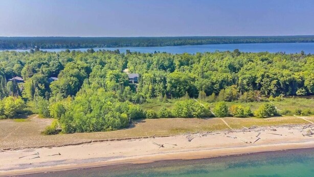 A coastal landscape with a beach, forested area, and a body of water.