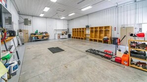 A spacious industrial interior with concrete floors, metal walls, and various tools and equipment.