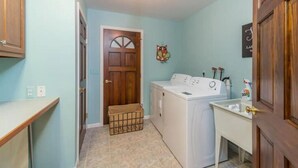 Una sala de lavandería con lavadora, tendedero y lavamanos.