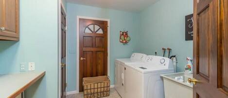 A laundry room with a washing machine, a drying rack, and a sink.