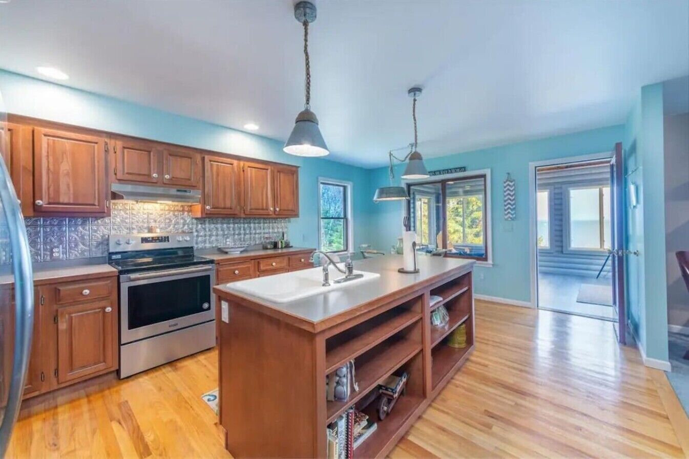 A modern kitchen with wooden cabinets, stainless steel appliances, and a central island.