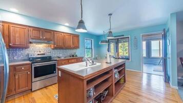 A modern kitchen with wooden cabinets, stainless steel appliances, and a central island.