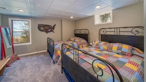 Un dormitorio con dos camas con estructura de metal, piso alfombrado, una ventana con vistas y un mapa en la pared.