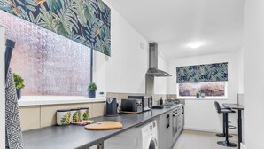 Una cocina moderna con lavadora, tostadora y ventana con vista a la playa.