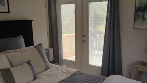 Une chambre à coucher avec un lit, une fenêtre et une porte donnant sur un balcon.