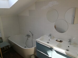 Une salle de bain moderne avec une baignoire sur pieds, un meuble-lavabo et trois miroirs fixés au mur.