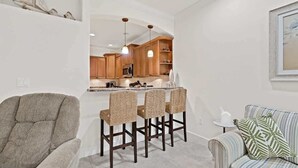 Uma cozinha moderna com armários de madeira, uma ilha central com banquetas e iluminação pendente.