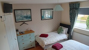 Un dormitorio con dos camas, un aparador y dos cuadros en la pared.