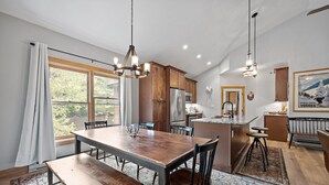 A spacious kitchen with wooden cabinets, a central island, and a dining area with a large table and benches. - Labor Day openings! (Woodstock)